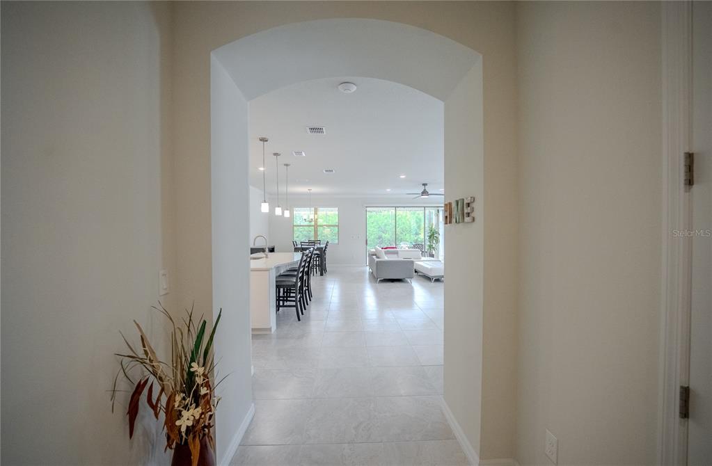 An arched entryway leads into an open-concept living area with tile floors and a kitchen — 9557 SW 64TH LANE, OCALA, FL