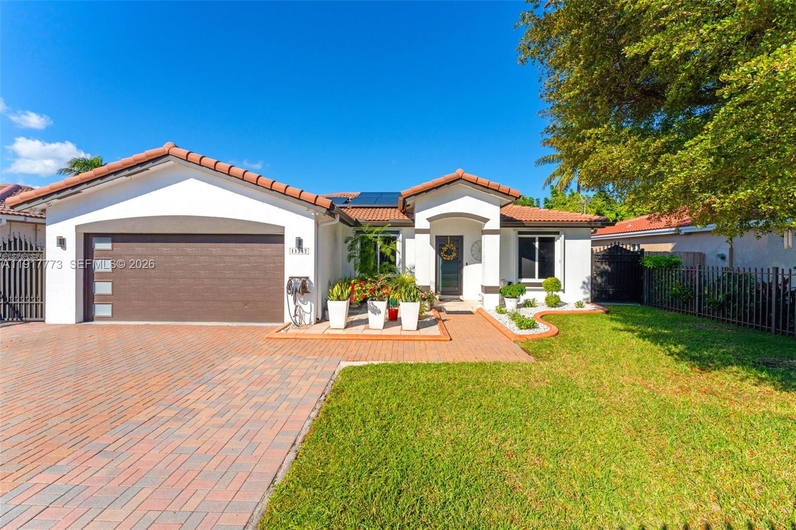 A single-story house with a tiled roof, white stucco exterior, and a brick driveway — 11347 SW 246th Ter, Homestead FL 33032, HOMESTEAD, FL