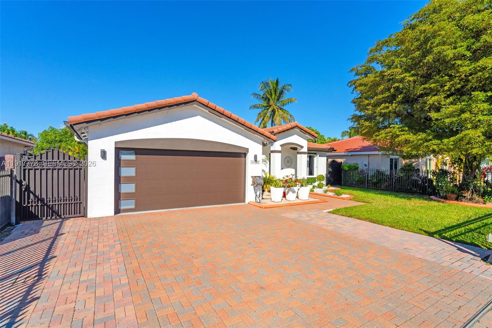 A single-story house with a white exterior, a brown garage door, and a brick driveway — 11347 SW 246th Ter, Homestead FL 33032, HOMESTEAD, FL