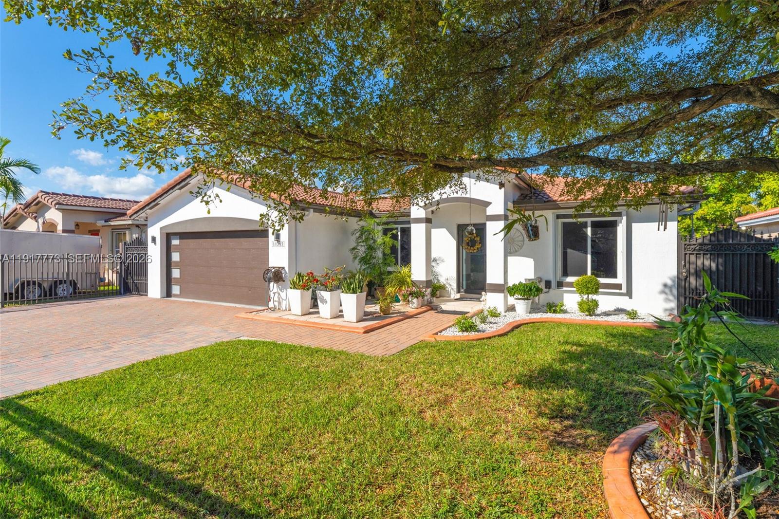 A single-story house with a brown garage door, white stucco walls, and a tiled roof — 11347 SW 246th Ter, Homestead FL 33032, HOMESTEAD, FL