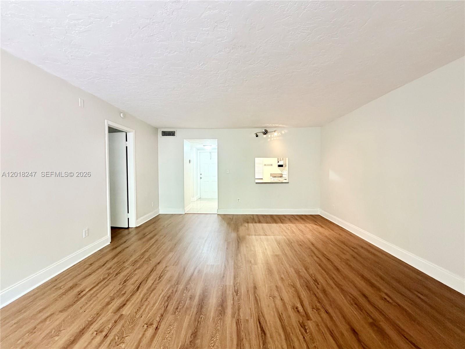 An empty room features light-colored walls, wood-look flooring, and a doorway leading to an entryway — 450 Commodore Dr # 214, Plantation FL 33325, PLANTATION, FL