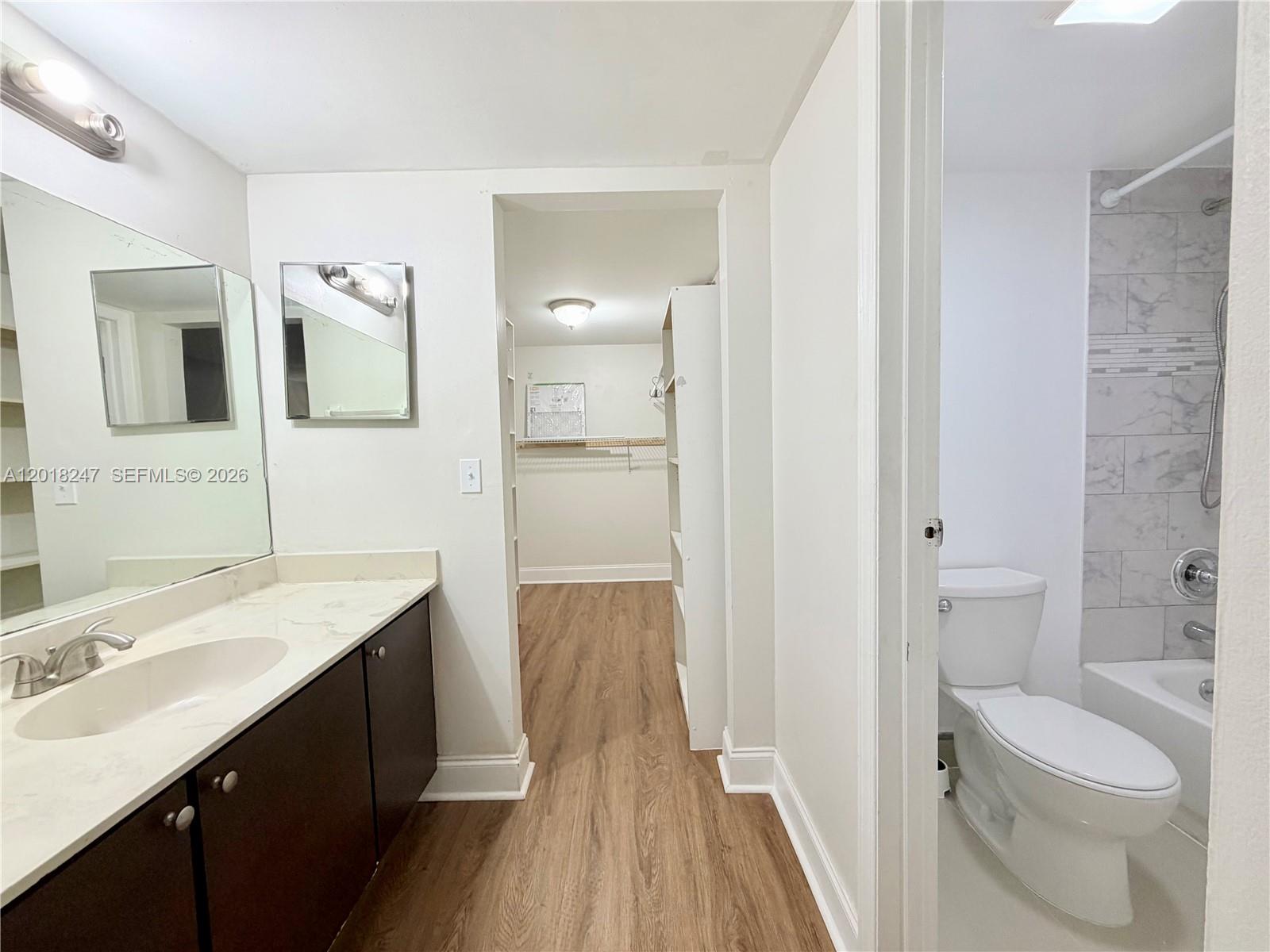A bathroom features a dark vanity, a walk-in closet, and a separate toilet area — 450 Commodore Dr # 214, Plantation FL 33325, PLANTATION, FL