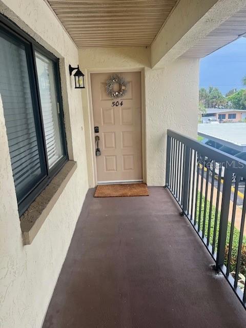 An exterior view of a balcony leading to a tan front door numbered 504 — 211 S 6TH STREET UNIT 504, COCOA BEACH, FL