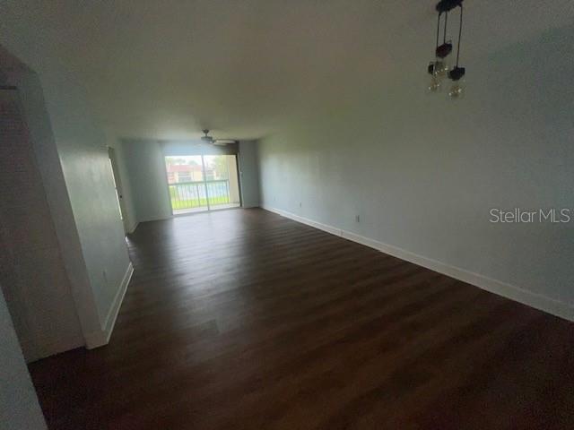 An empty living room features wood-look flooring, light blue walls, and a sliding glass door — 211 S 6TH STREET UNIT 504, COCOA BEACH, FL