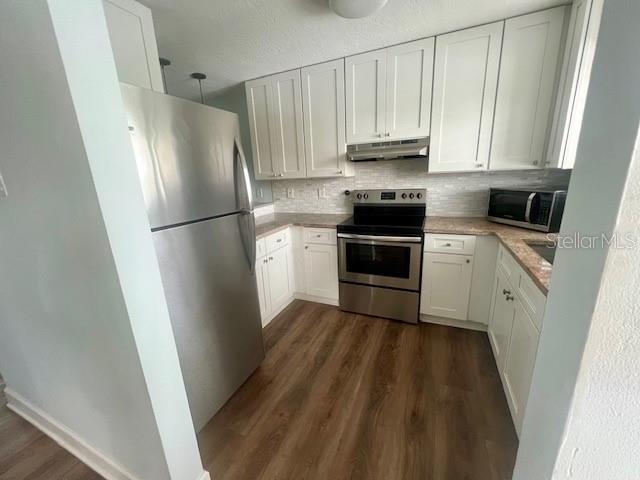 A kitchen features white cabinets, stainless steel appliances, and wood-look flooring — 211 S 6TH STREET UNIT 504, COCOA BEACH, FL