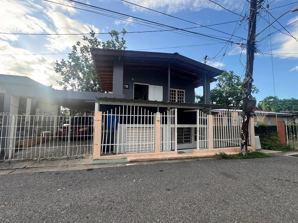 A two-story house with a carport, white metal fencing, and a dark gray exterior — Galniel #A44 BARRIADA GARNIER, MAYAGUEZ, PR