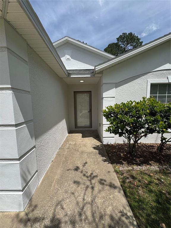 A concrete walkway leads to the front entrance of a white stucco house — 12 REYNOLDS PLACE, PALM COAST, FL