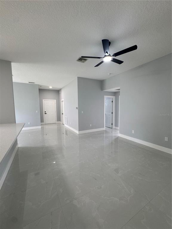 A bright, open-concept living area features light gray walls, white trim, and polished tile flooring — 12 REYNOLDS PLACE, PALM COAST, FL