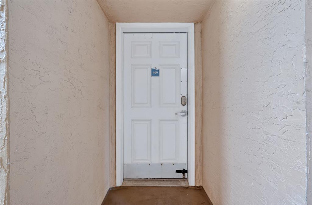 A white six-panel door with a number 409 tag is set in a stucco alcove — 421 S ATLANTIC AVENUE UNIT 409, NEW SMYRNA BEACH, FL