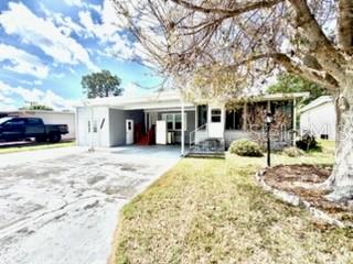 A single-story house with a carport, a paved driveway, and a large tree in front — 194 ROSEWOOD DRIVE, COCOA, FL