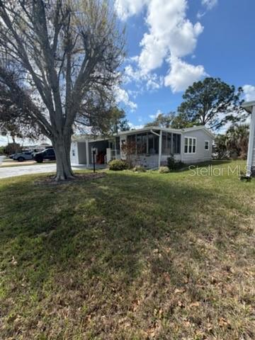 A light-colored mobile home with a screened-in porch sits on a grassy lot — 194 ROSEWOOD DRIVE, COCOA, FL