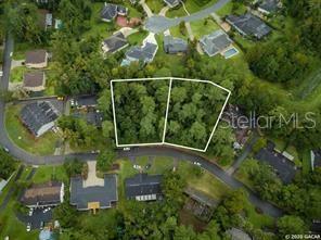 An aerial view shows two adjacent wooded residential lots outlined in white along a curved street — 2804 NW 104TH COURT, GAINESVILLE, FL