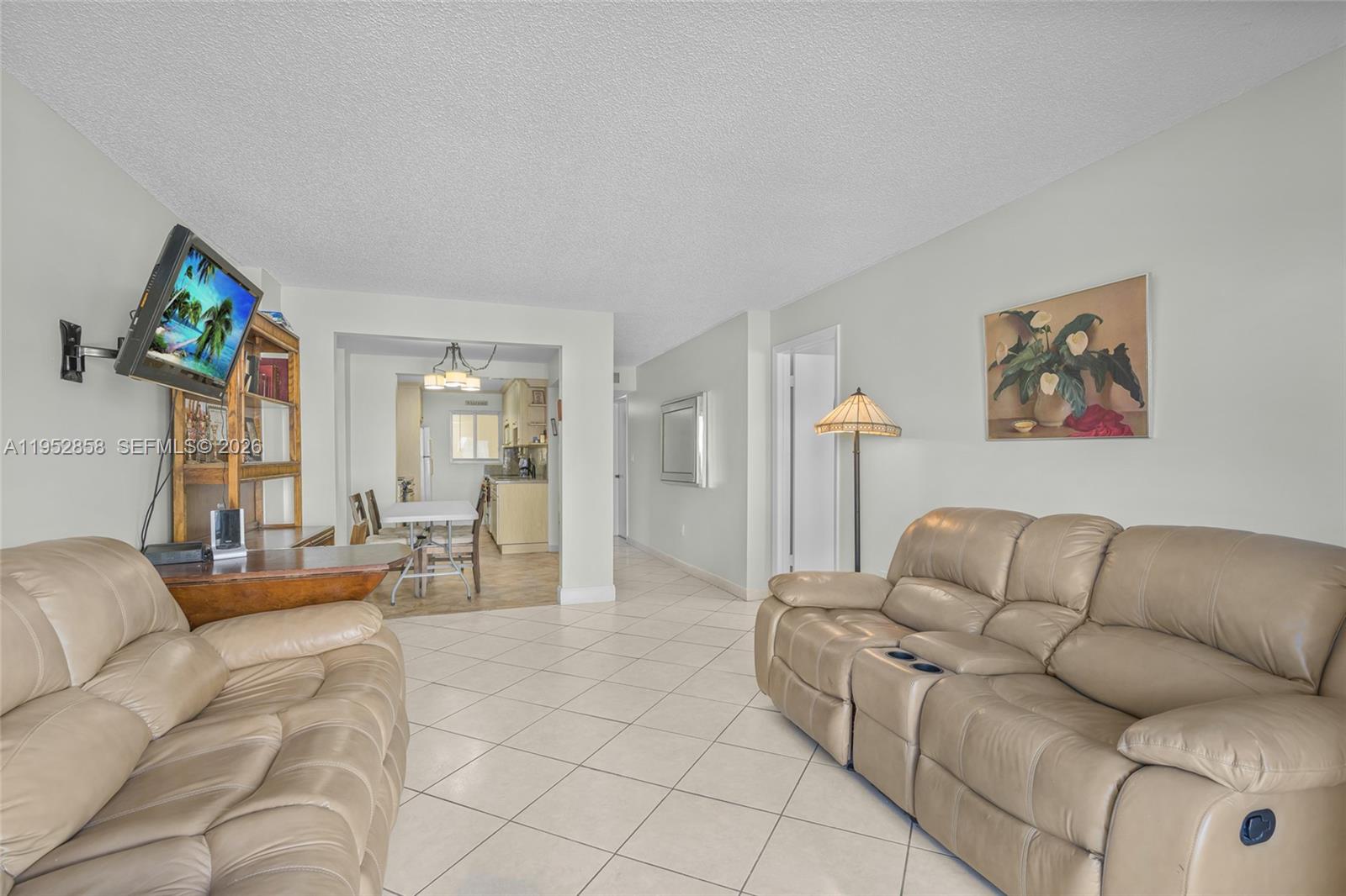 A living room features beige leather sofas, tile flooring, and an adjacent dining area — 4141 Collins Ave # 201, Miami Beach FL 33140, MIAMI BEACH, FL