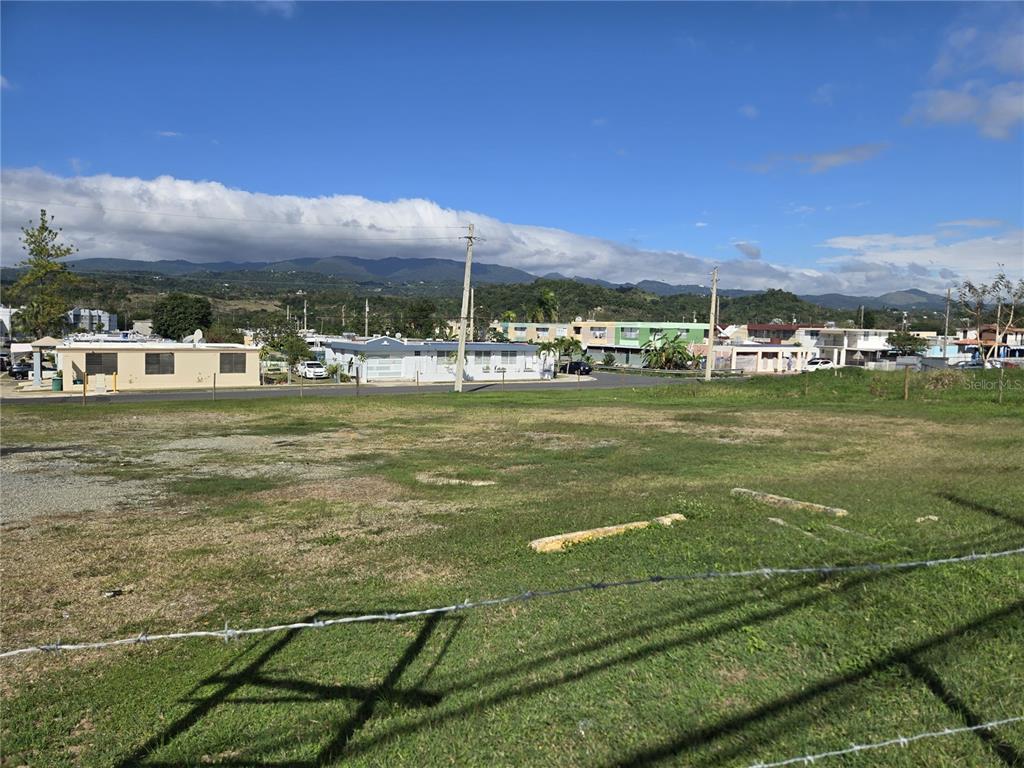 A vacant, grassy lot with a barbed wire fence in the foreground and distant mountains — 102 carr AVE. UNIVERSIDAD INTERAMERICANA, SAN GERMAN, PR