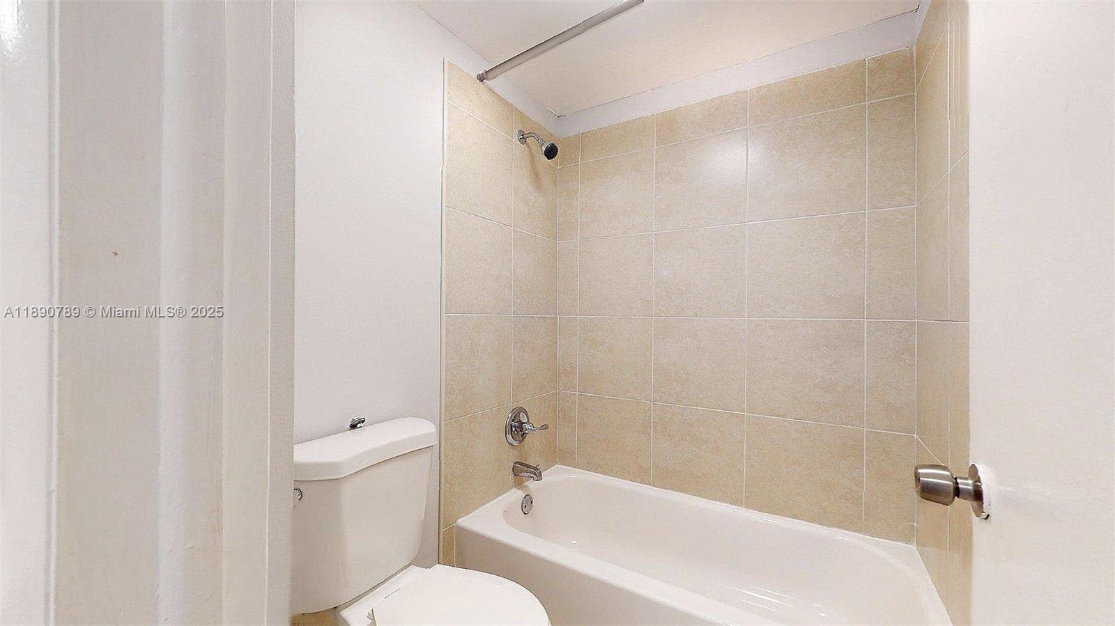 A bathroom features a white toilet, a bathtub, and beige tiled shower walls — 4850 SW 63rd Ter # 131, Davie FL 33314, DAVIE, FL