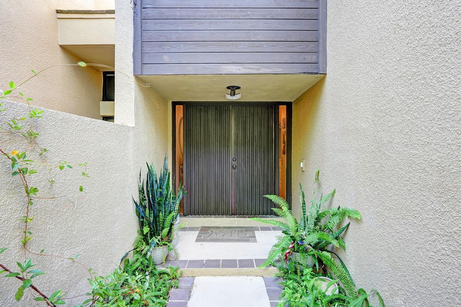 A recessed entryway features double doors with vertical slats, a concrete path, and potted plants — 702 Saint Albans Drive # 702, Boca Raton FL 33486, BOCA RATON, FL