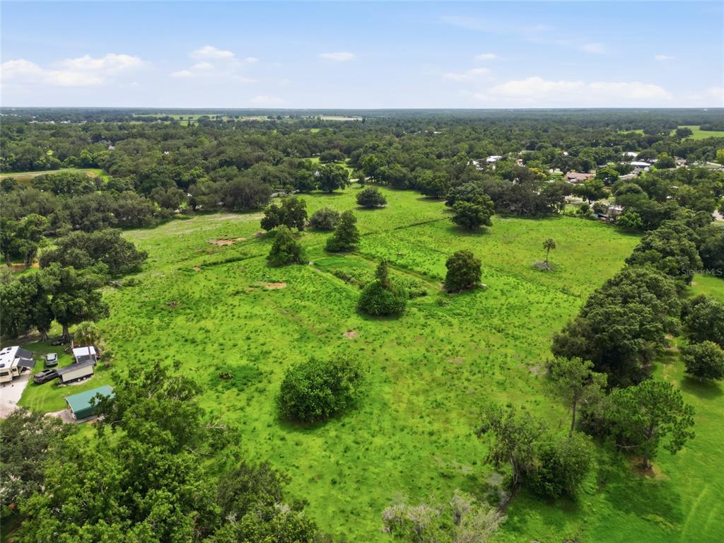 An aerial view shows a large, grassy pasture dotted with trees and some small structures — 1823 NE HAMMOCK STREET, ARCADIA, FL