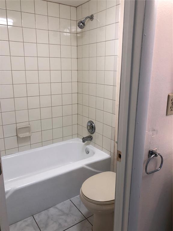 A bathroom features a white tiled shower-tub combination and a beige toilet — 2616 LEMON TREE LANE UNIT F, ORLANDO, FL