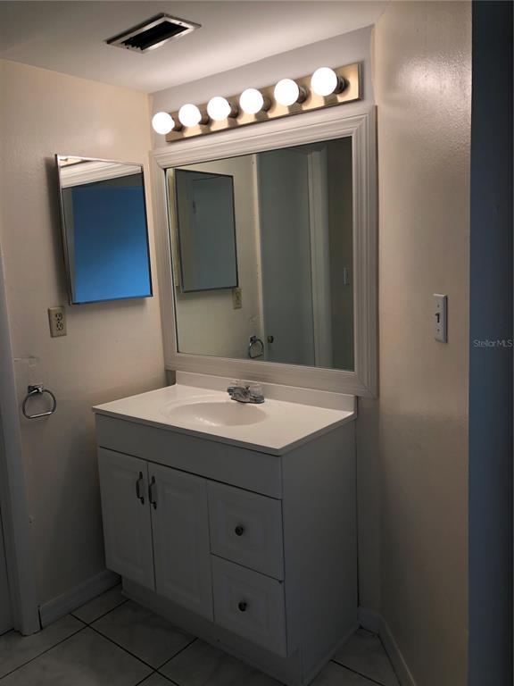 A bathroom vanity with a white cabinet, sink, large mirror, and overhead light fixture — 2616 LEMON TREE LANE UNIT F, ORLANDO, FL