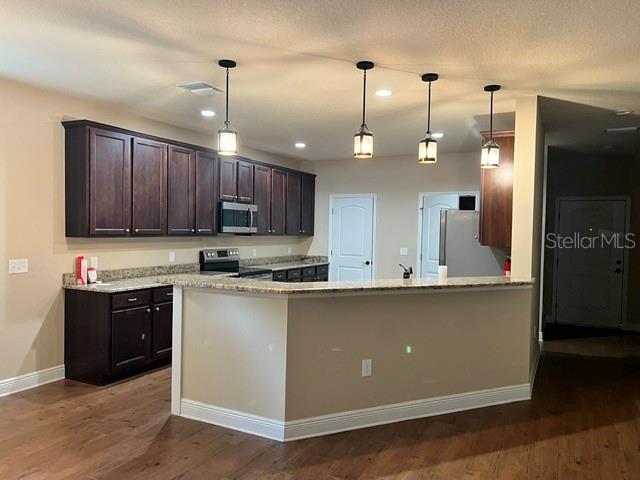 A kitchen features dark wood cabinets, granite countertops, and three pendant lights over a peninsula — 421 E PARK STREET, LAKELAND, FL