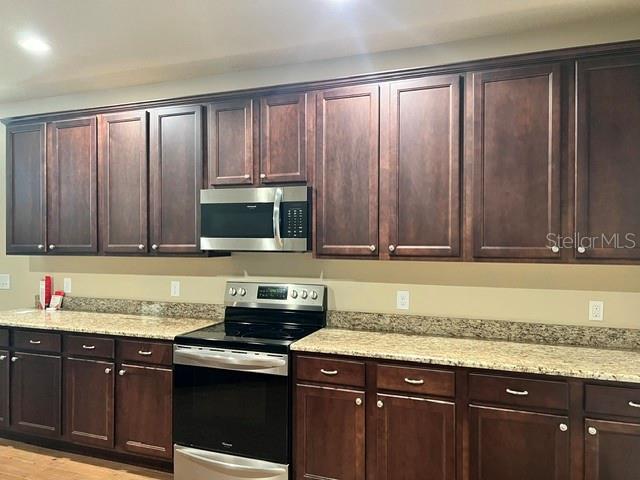 A kitchen features dark wood cabinets, granite countertops, and stainless steel appliances — 421 E PARK STREET, LAKELAND, FL