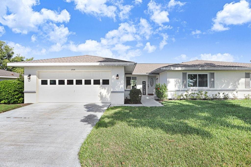 A single-story house with a white exterior, a two-car garage, and a front lawn — 2306 LANCASTER DRIVE UNIT 2306, SUN CITY CENTER, FL