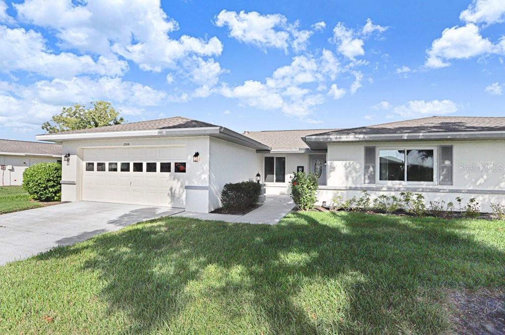 A single-story house with a white exterior, a two-car garage, and a front lawn — 2306 LANCASTER DRIVE UNIT 2306, SUN CITY CENTER, FL