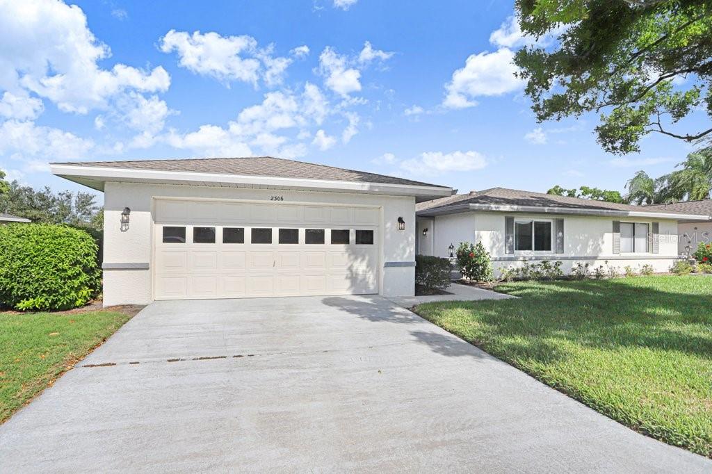 A single-story house with a white exterior, a two-car garage, and a concrete driveway — 2306 LANCASTER DRIVE UNIT 2306, SUN CITY CENTER, FL