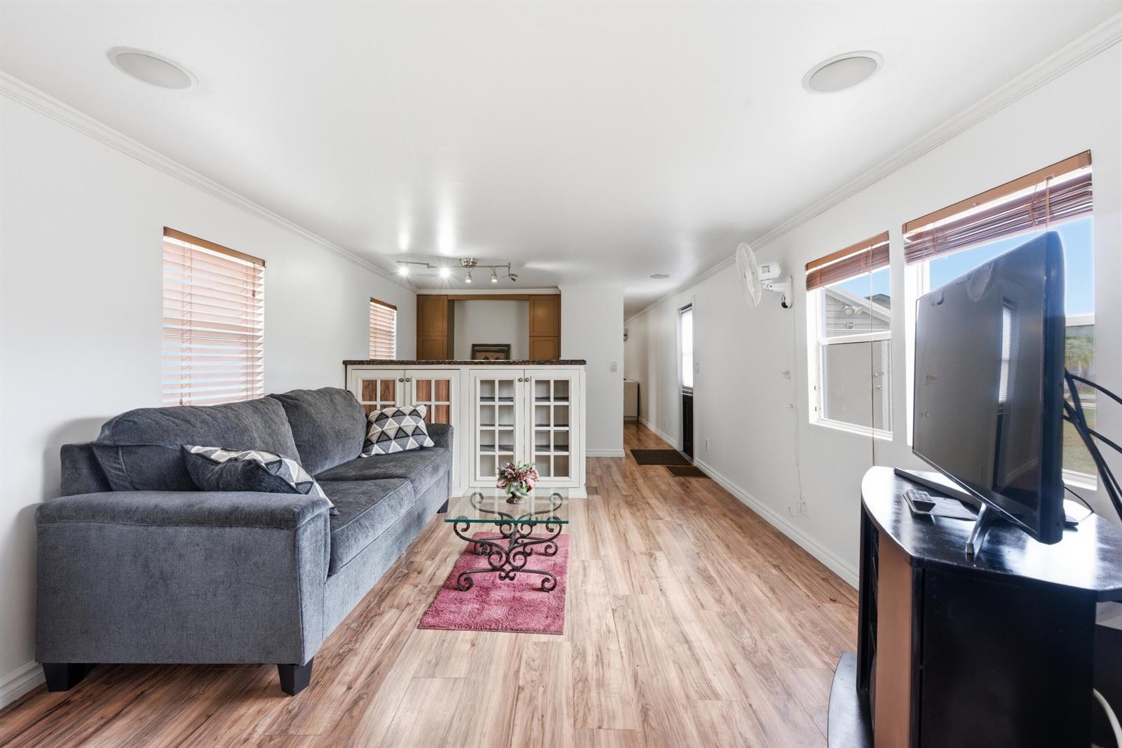A living room features a grey sofa, a glass coffee table, and wood-look flooring — 12375 S Military Trail # 188, Boynton Beach FL 33436, BOYNTON BEACH, FL