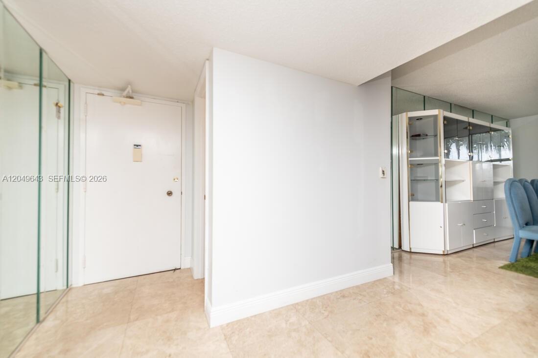 A white door stands in a tiled entryway next to a mirrored wall and cabinet — 1985 S Ocean Dr # 2Q, Hallandale Beach FL 33009, HALLANDALE BEACH, FL