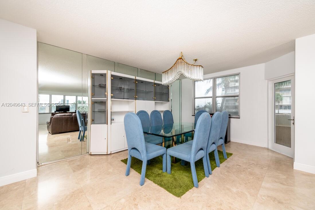 A dining room features a glass table, blue chairs, a green rug, and mirrored walls — 1985 S Ocean Dr # 2Q, Hallandale Beach FL 33009, HALLANDALE BEACH, FL
