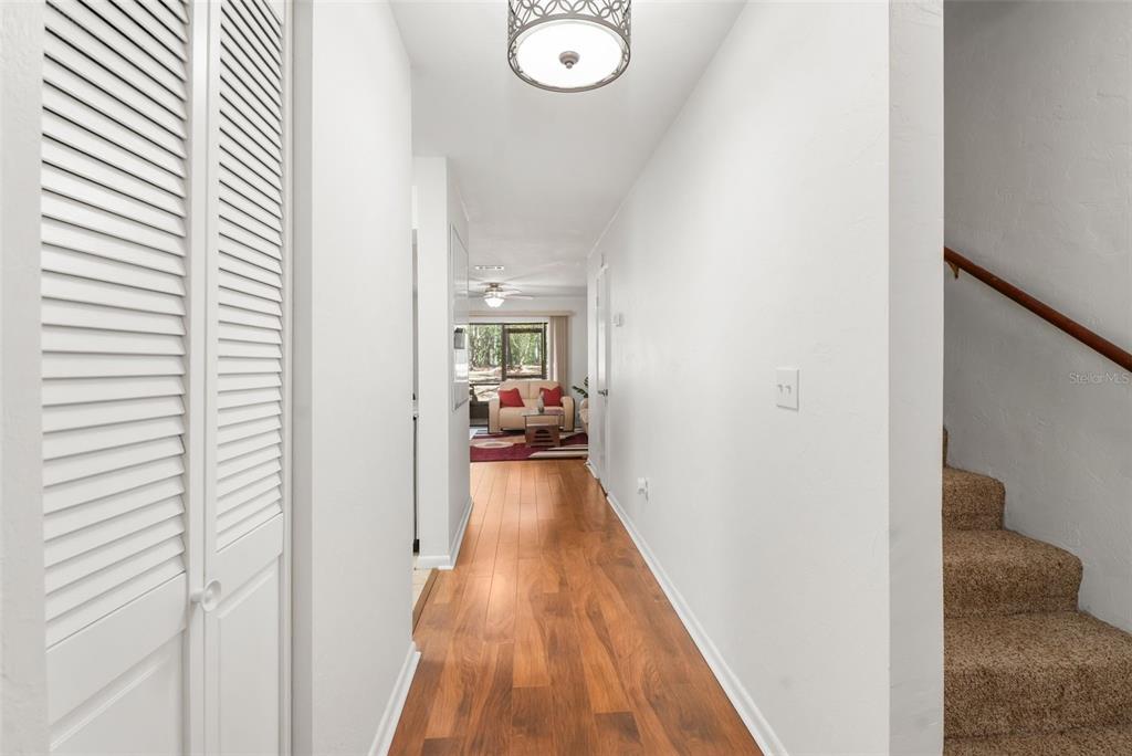 A hallway with wood-look flooring leads to a living area with a staircase on the right — 2735 SW 35TH PLACE UNIT 903, GAINESVILLE, FL