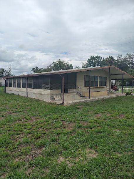 A single-story manufactured home with a screened-in porch and a covered carport — 38553 ALSTON AVENUE, ZEPHYRHILLS, FL