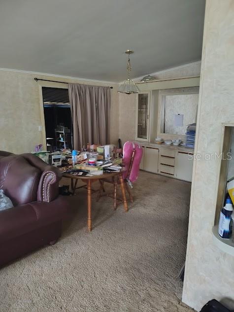 A dining area with a round wooden table sits adjacent to a living room space — 38553 ALSTON AVENUE, ZEPHYRHILLS, FL