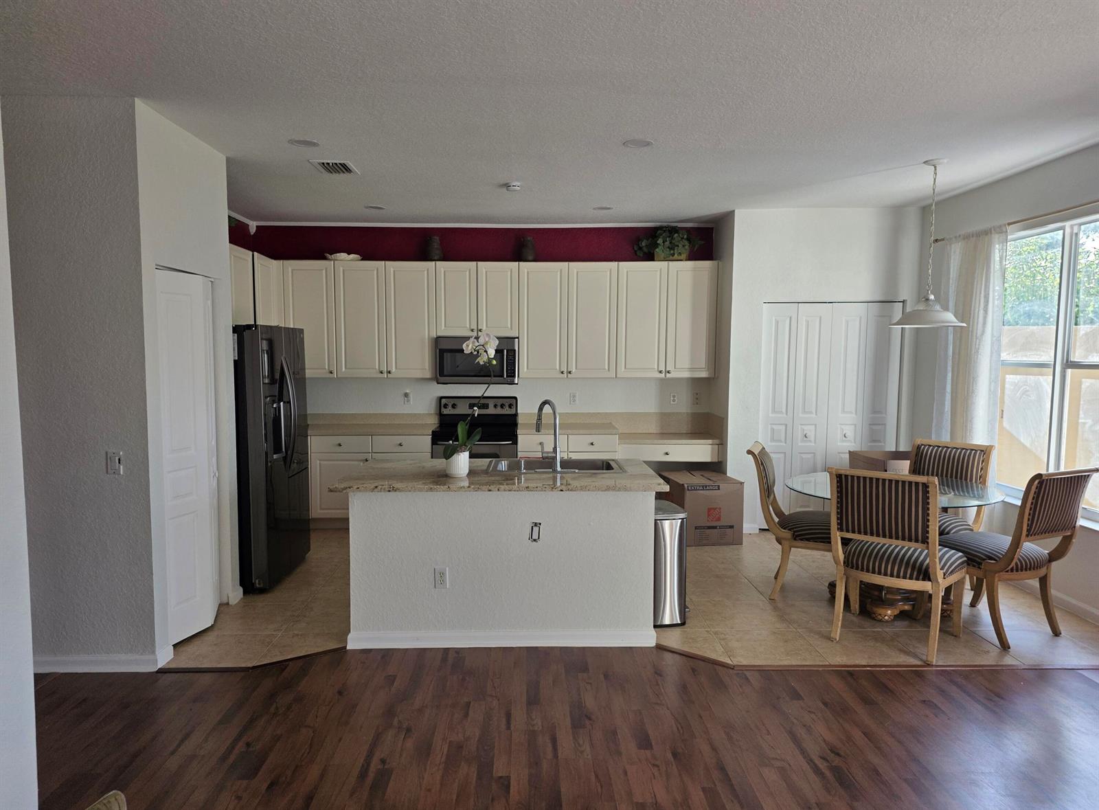 A kitchen with white cabinets, granite countertops, a center island, and an adjacent dining area — 5069 Starblaze Drive, FL 33463, FL