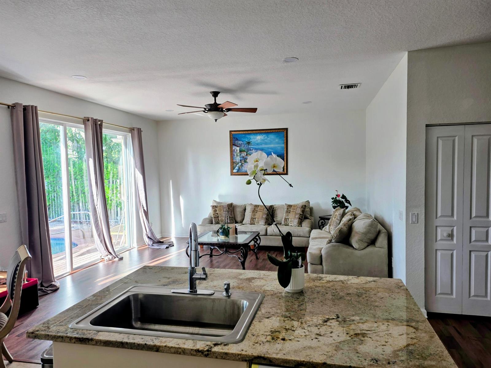 A kitchen island with a granite countertop overlooks a living room with a sofa set — 5069 Starblaze Drive, FL 33463, FL