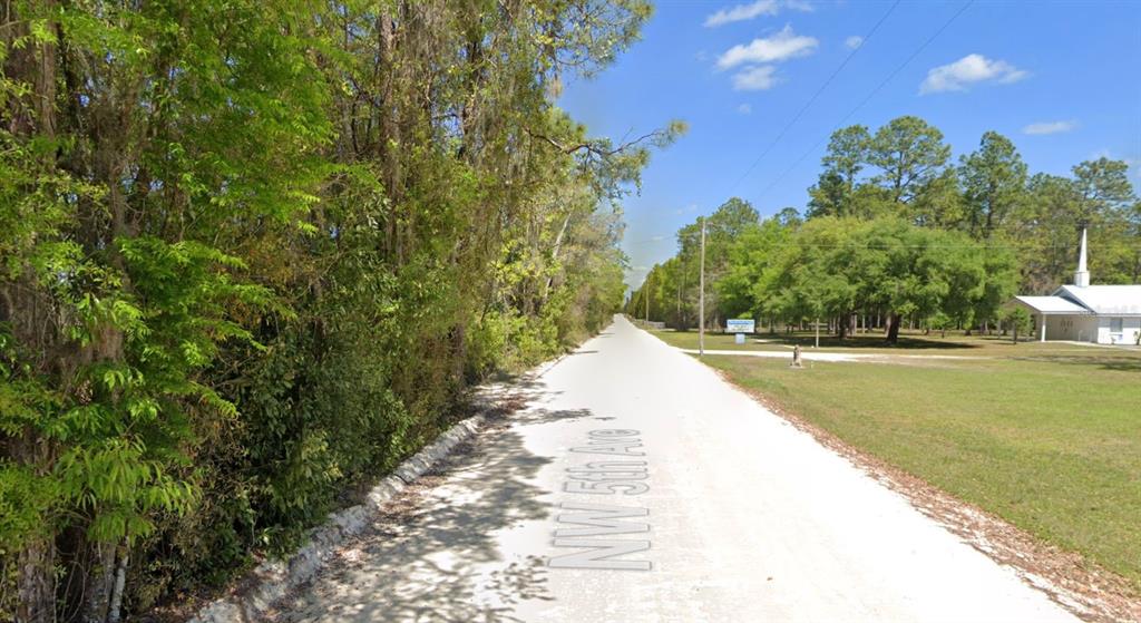 A dirt road runs between a dense line of trees and a grassy church lot — OFF NW CR 138 Lot 71, BRANFORD, FL
