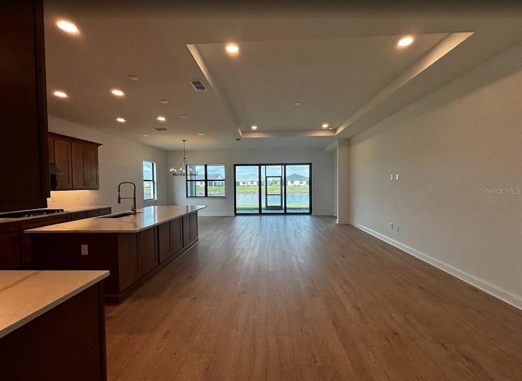 An open-concept kitchen and living area features dark wood cabinetry, a large island, and flooring — 5615 FREESTONE CIRCLE, APOLLO BEACH, FL
