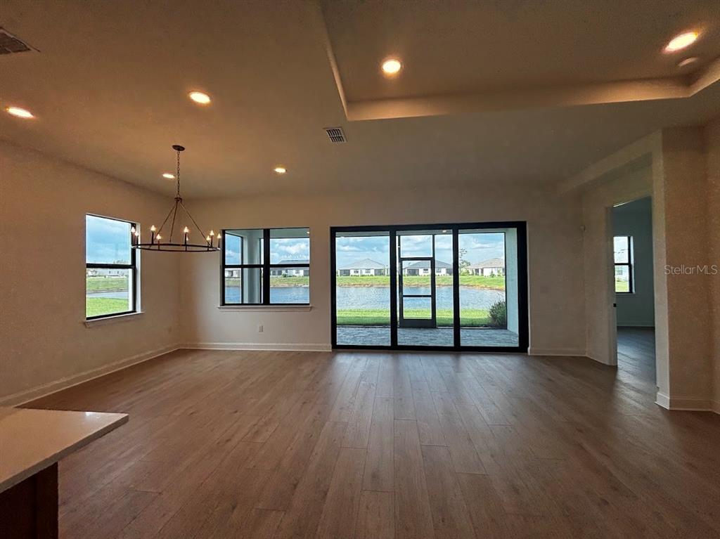 An open-concept living area features light wood flooring, a modern chandelier, and large sliding glass doors — 5615 FREESTONE CIRCLE, APOLLO BEACH, FL
