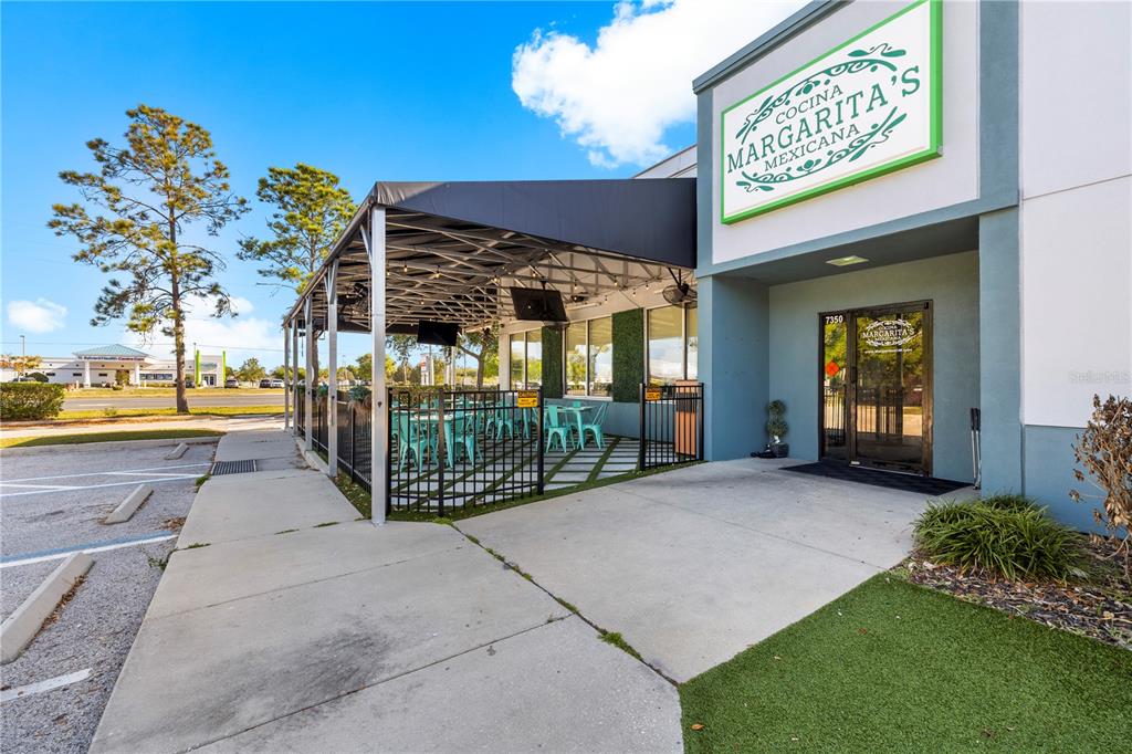 The exterior of a restaurant features a covered outdoor patio with seating and signage — 7350 CYPRESS GARDENS BOULEVARD, WINTER HAVEN, FL