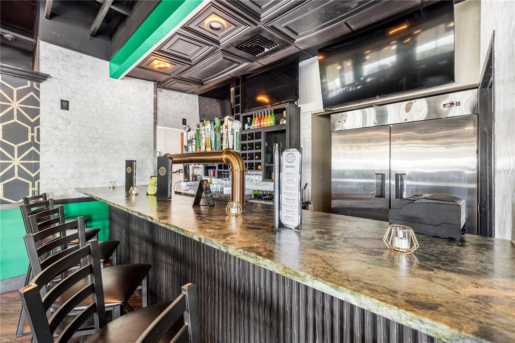 A bar area features a stone countertop, dark ribbed cabinetry, and a black coffered ceiling — 7350 CYPRESS GARDENS BOULEVARD, WINTER HAVEN, FL