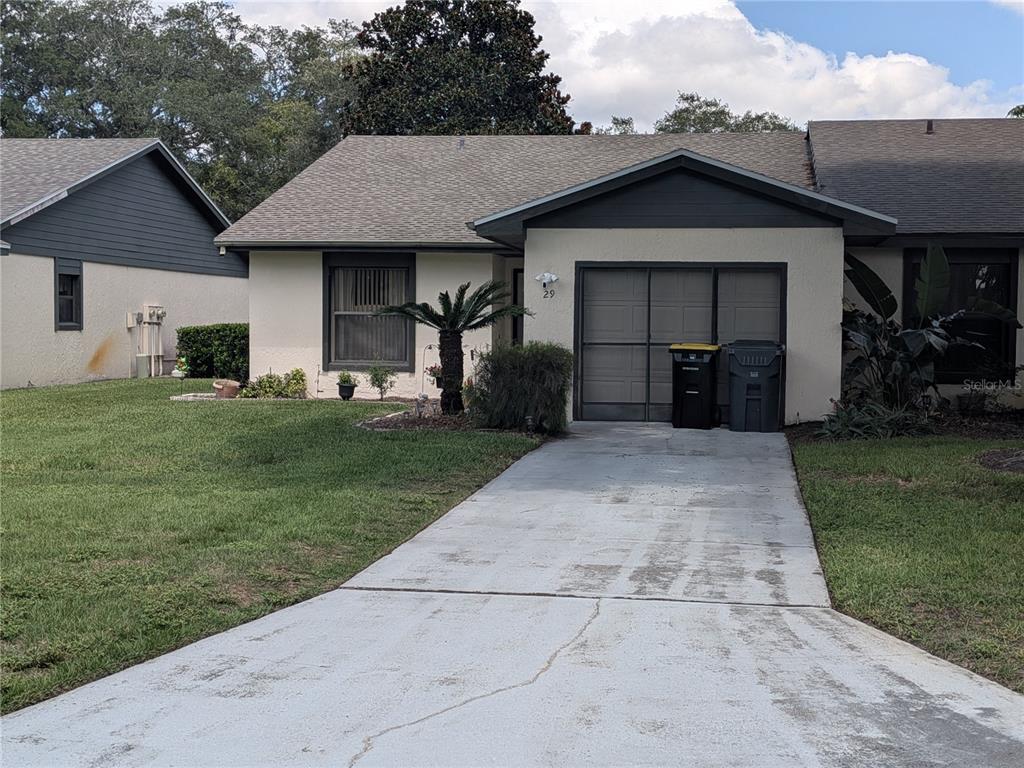 A single-story house with a concrete driveway, a garage, and a front lawn — 29 BUCK CIRCLE, HAINES CITY, FL