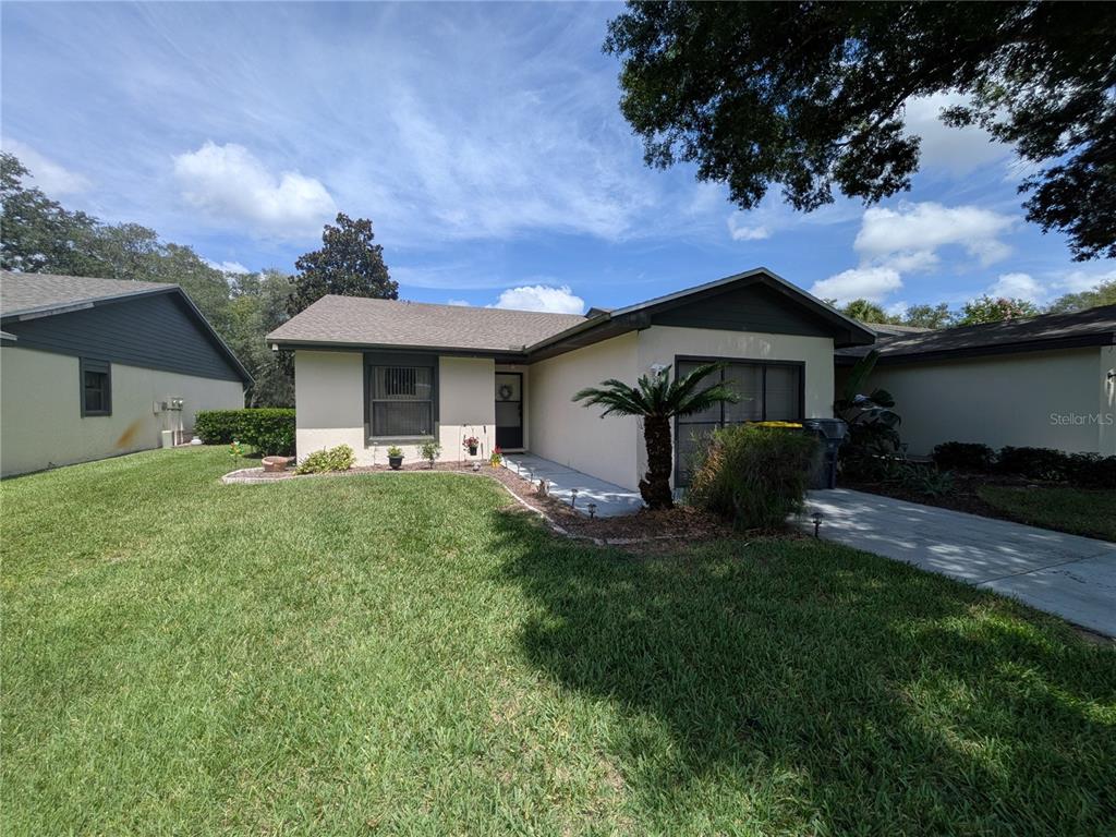 A single-story house with a beige stucco exterior, a gray shingled roof, and a front lawn — 29 BUCK CIRCLE, HAINES CITY, FL