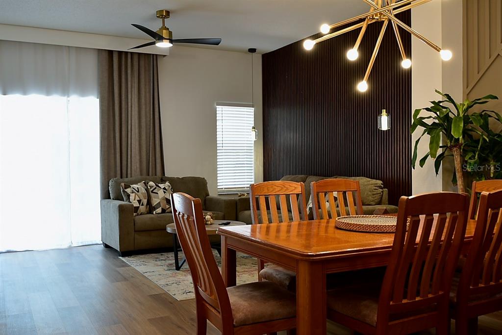 A dining area with a wooden table and chairs sits before a dark slatted wall — 1043 PARK RIDGE CIRCLE, KISSIMMEE, FL