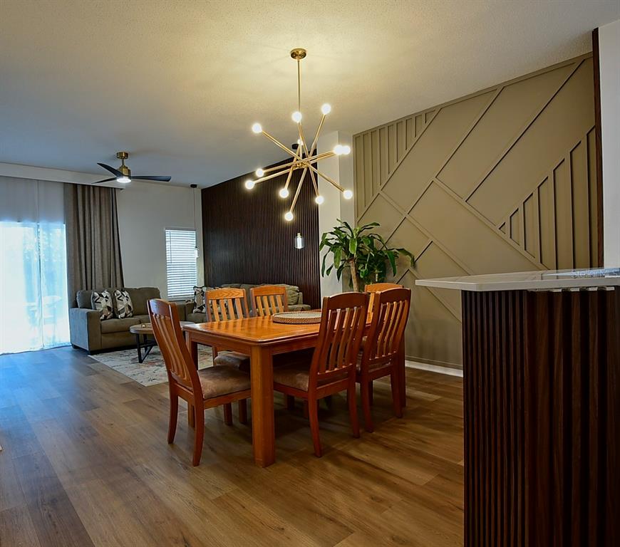 A dining area features a modern sputnik chandelier, wood furniture, and a geometric accent wall — 1043 PARK RIDGE CIRCLE, KISSIMMEE, FL