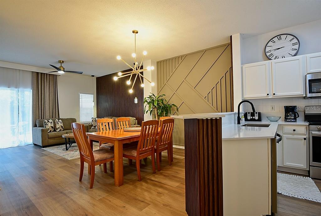 A dining area with a wood-slat accent wall sits adjacent to a kitchen and living room — 1043 PARK RIDGE CIRCLE, KISSIMMEE, FL