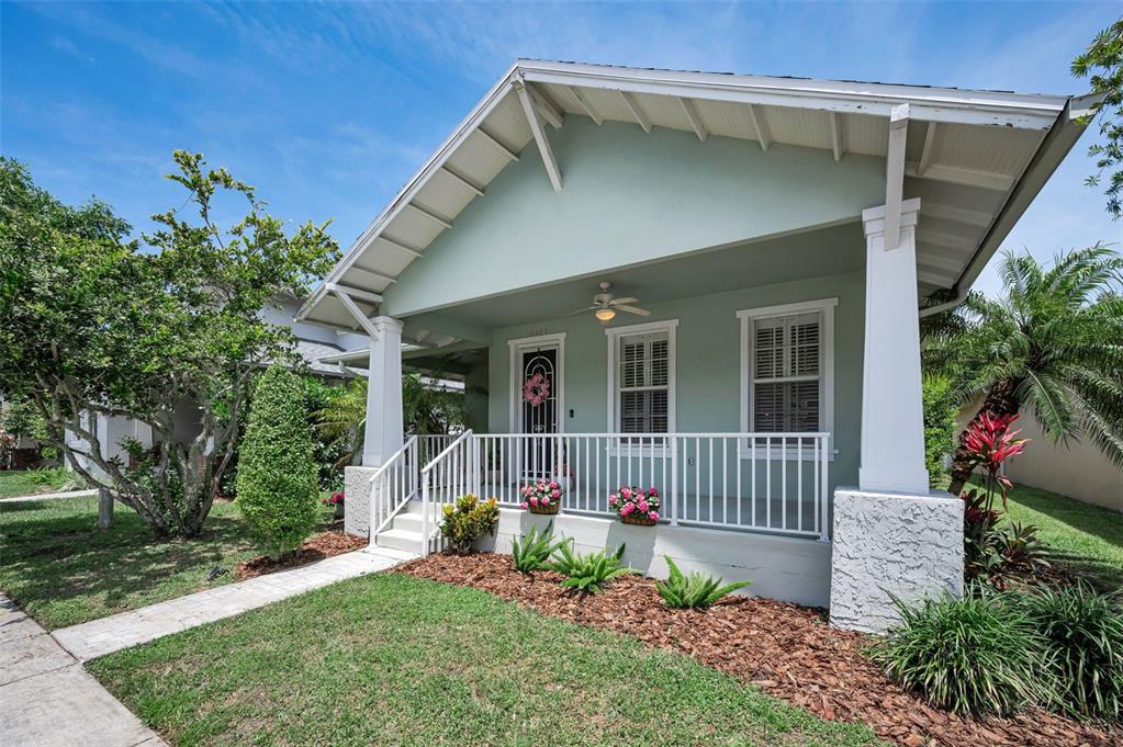 A light green bungalow features a covered front porch with white railings and columns — 10403 MICANOPY STREET, NEW PORT RICHEY, FL