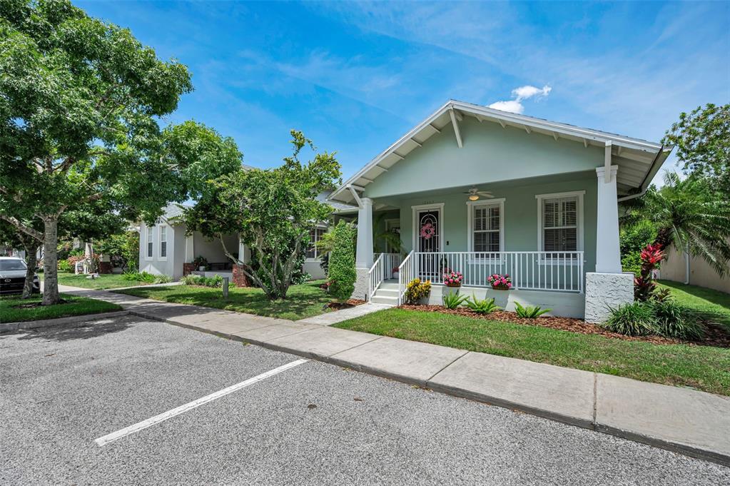 A light green bungalow with a covered front porch and white railings sits near a parking lot — 10403 MICANOPY STREET, NEW PORT RICHEY, FL