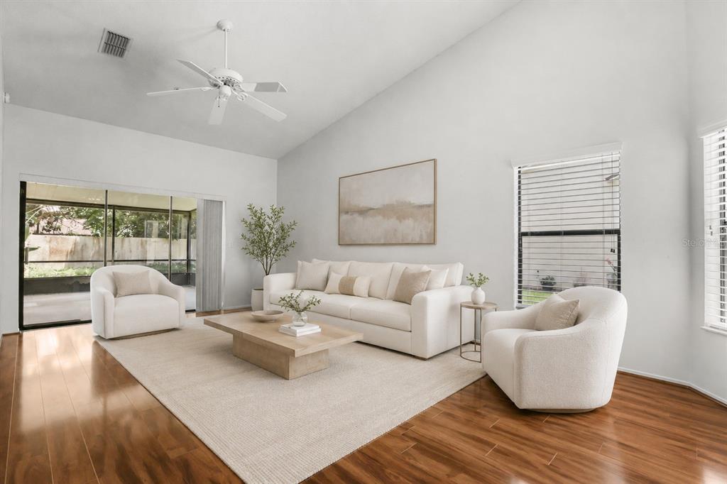 A bright living room with a vaulted ceiling, white sofa, two armchairs, and hardwood floors — 223 HERON STREET, ALTAMONTE SPRINGS, FL