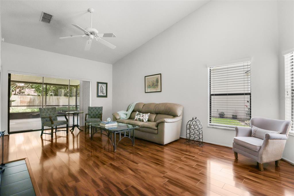 A living room with hardwood floors, a vaulted ceiling, a ceiling fan, and sliding glass doors — 223 HERON STREET, ALTAMONTE SPRINGS, FL